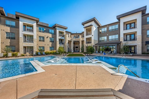 A large swimming pool in front of apartment buildings.