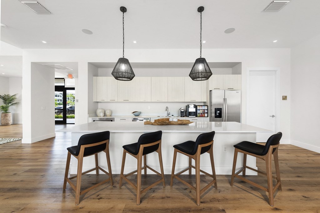 a kitchen with white cabinets and a large island with three stools in front of it