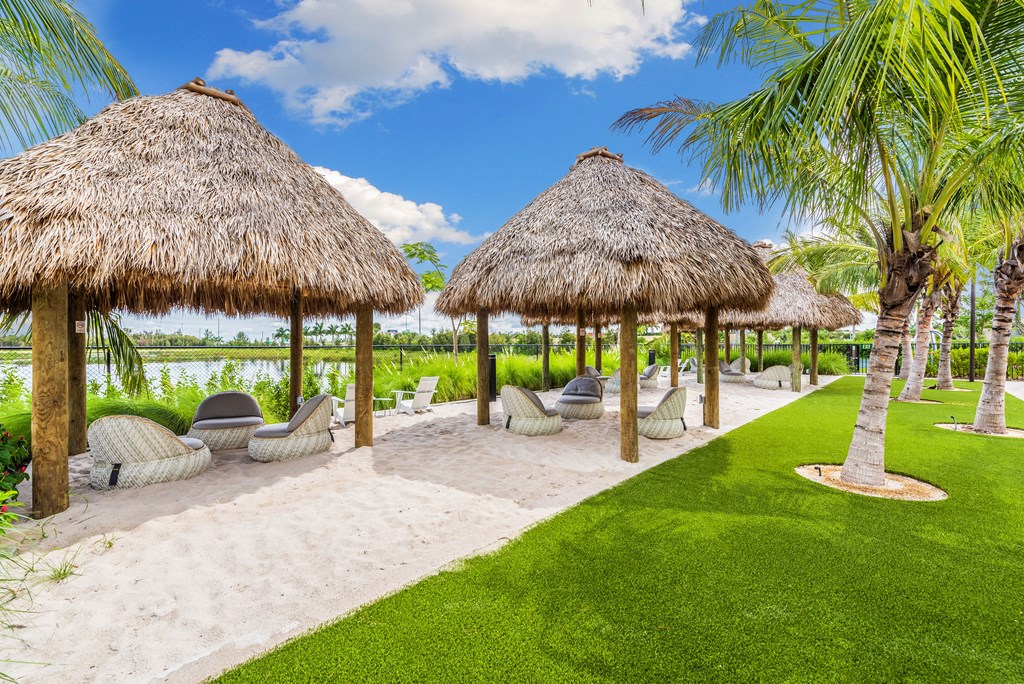 a thatched gazebo with lounge chairs and palm trees