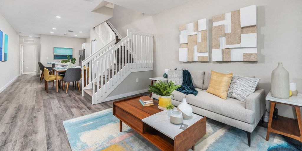 a living room with a staircase in the background and a colorful rug in the foreground