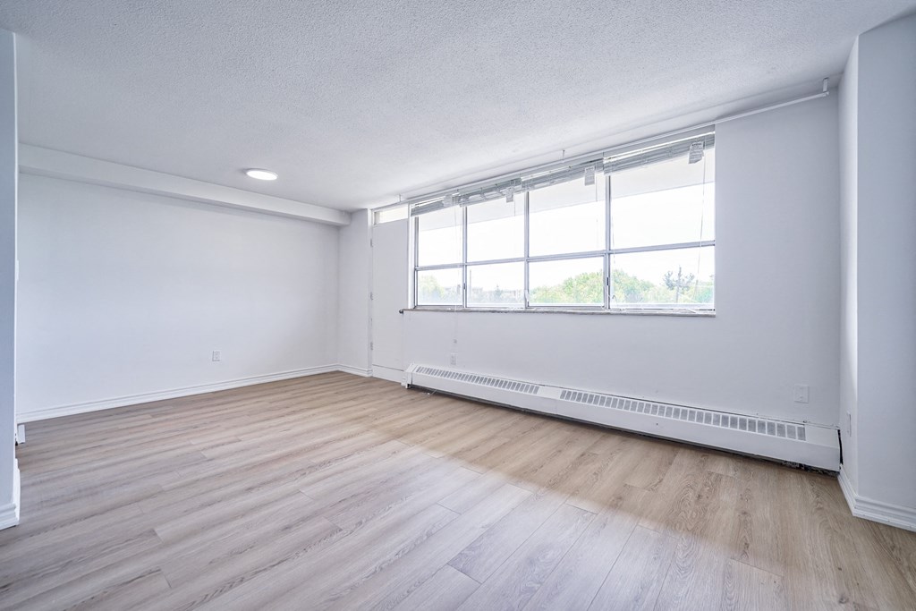 an empty living room with wood floors and a large window