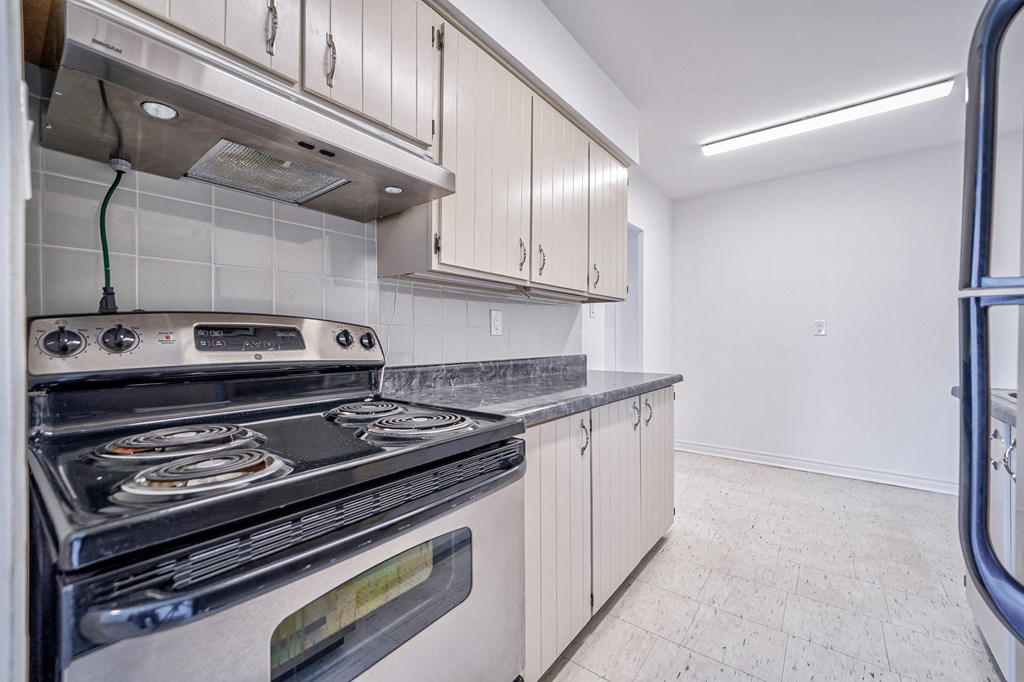an empty kitchen with white cabinets and stainless steel appliances