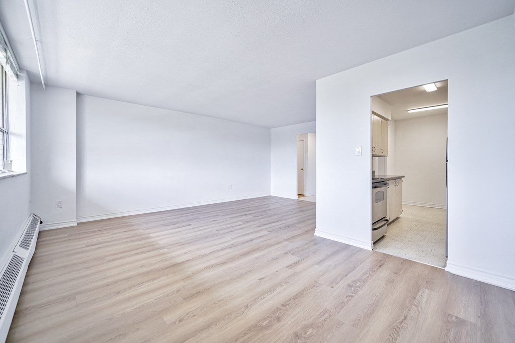 a living room and kitchen with wood floors and white walls