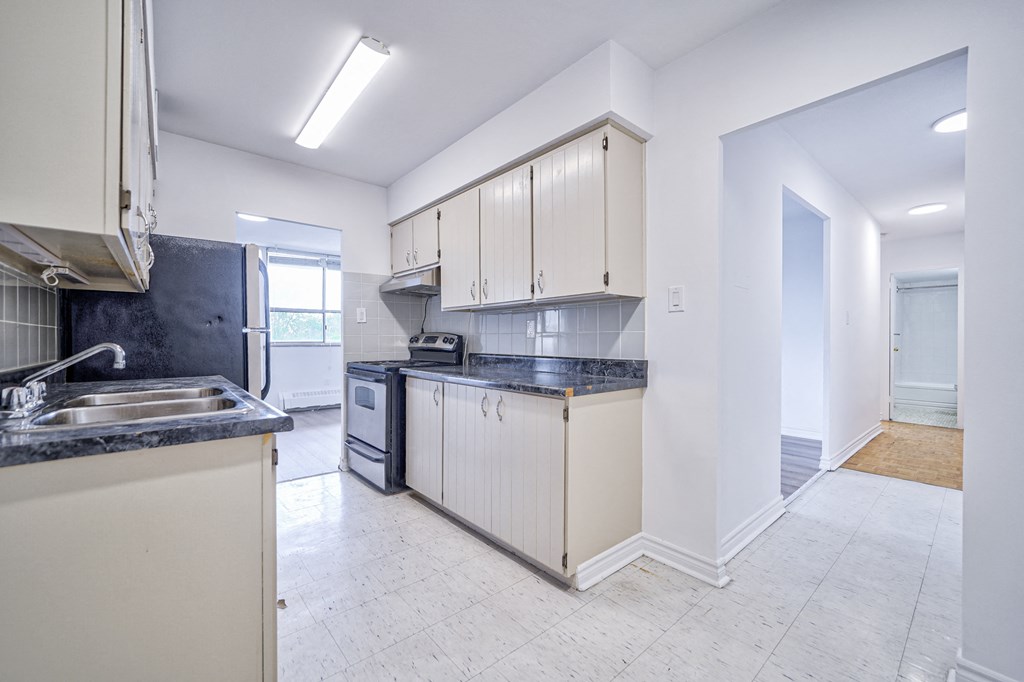 a kitchen with white cabinets and black counter tops and a sink