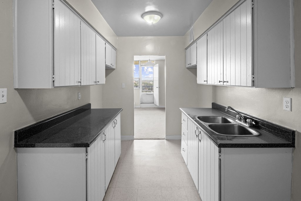 an empty kitchen with white cabinets and a sink