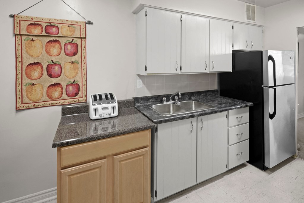 a kitchen with white cabinets and a sink and a refrigerator