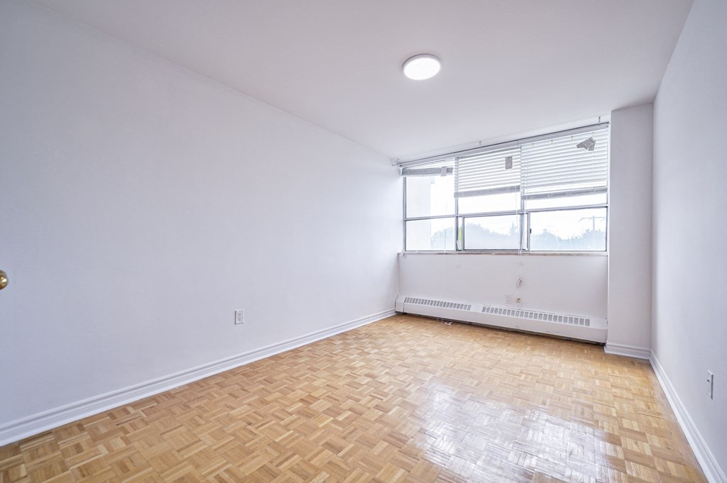 an empty living room with wood flooring and a window
