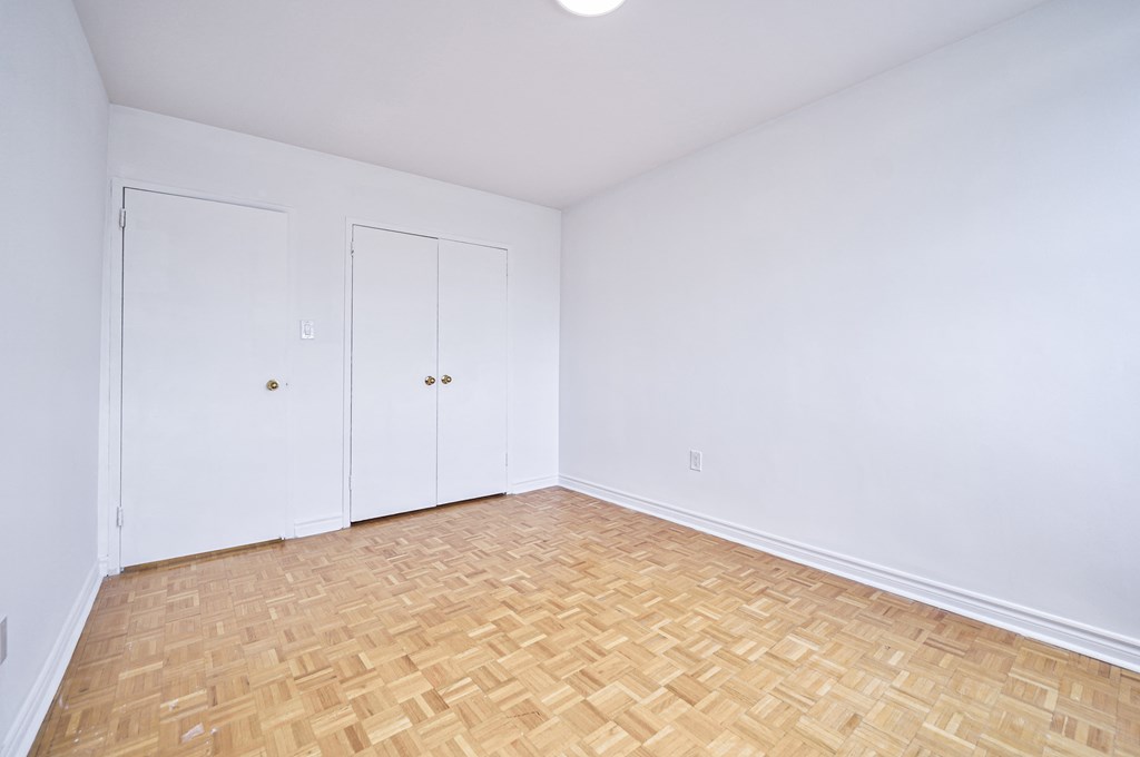 an empty room with white walls and wood flooring