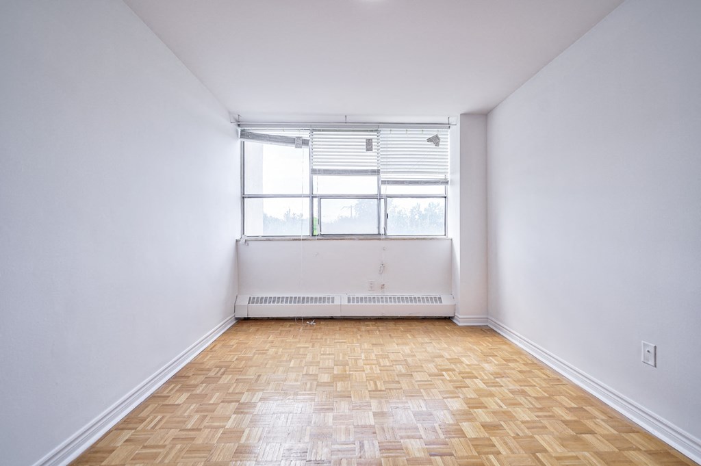 an empty room with a window and wooden floors