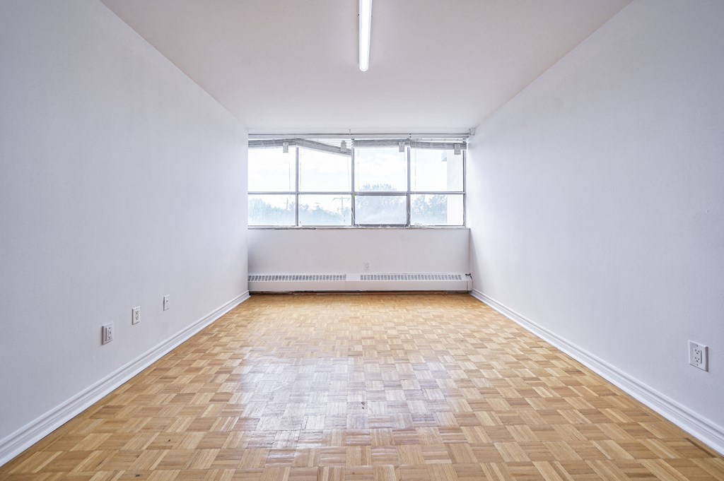 an empty room with wood flooring and a window