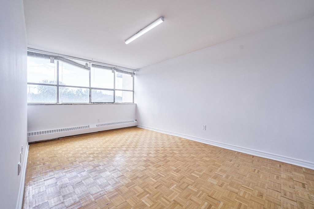 an empty room with wood flooring and a window