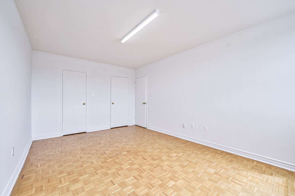 an empty room with white walls and wood flooring