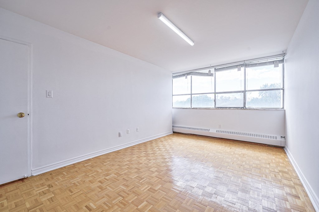 an empty living room with wood flooring and a window