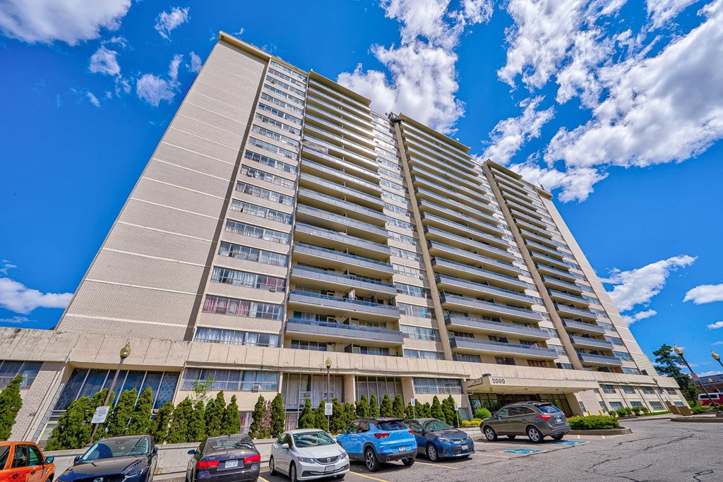 an image of an apartment building with cars parked in front of it