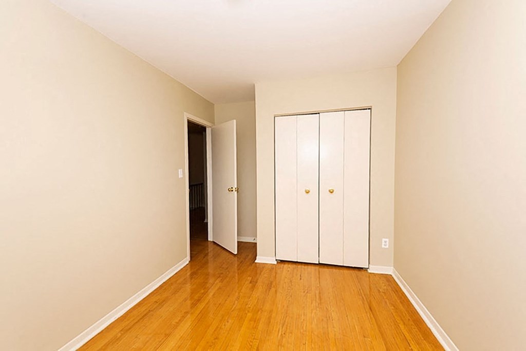 a bedroom with a wood floor and a closet