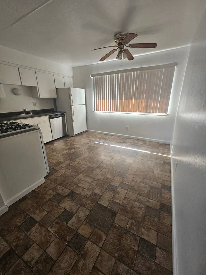 an empty kitchen and living room with a ceiling fan