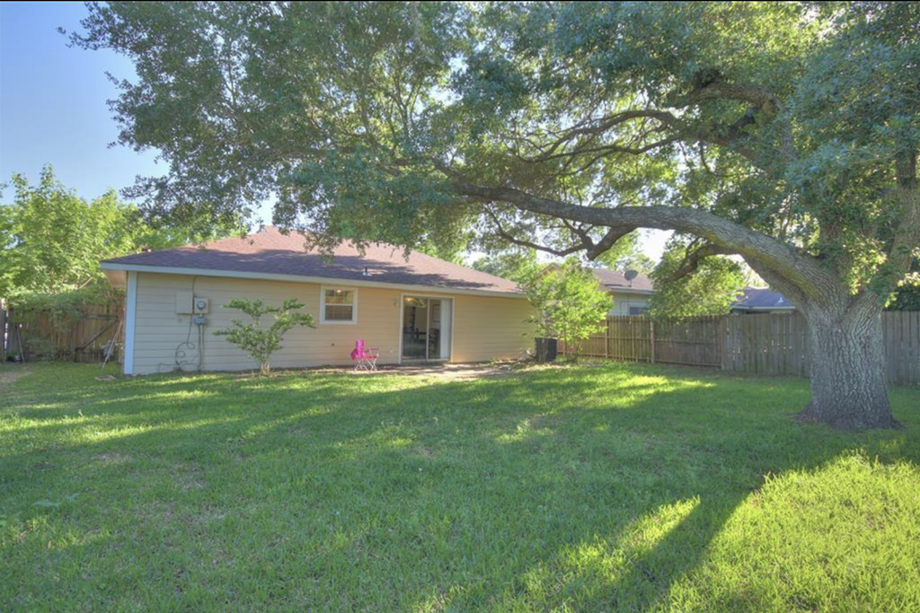 a house with a large yard and a large tree in front of it