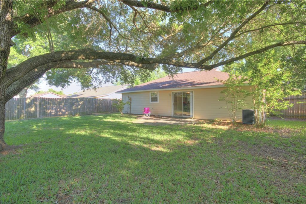 a home with a large yard and a large tree in front of it