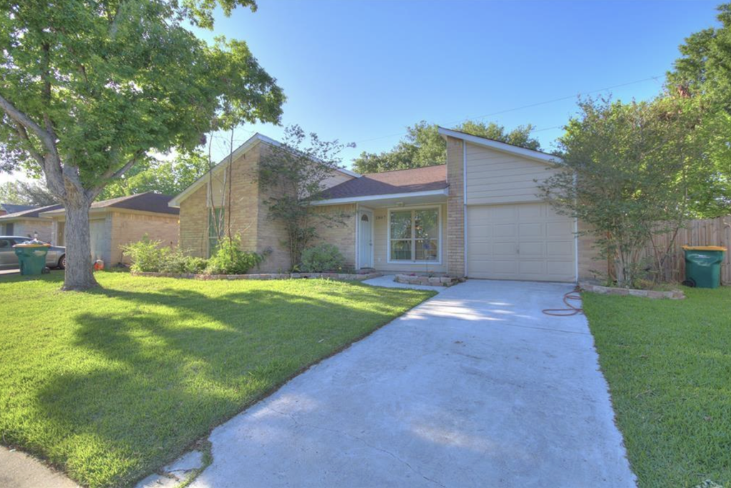 a house with a driveway and lawn in front of it