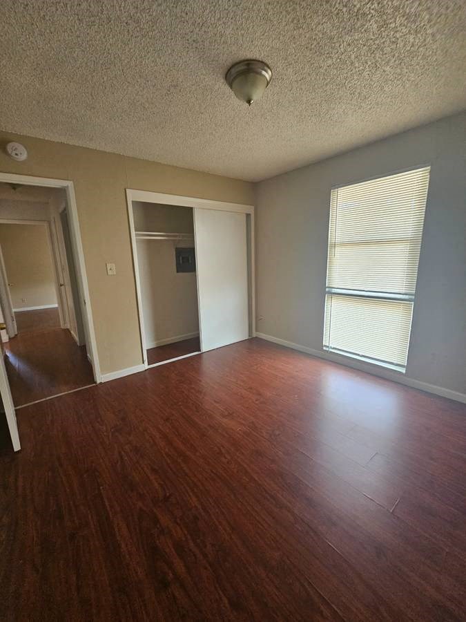 an empty room with a large window and wooden floors