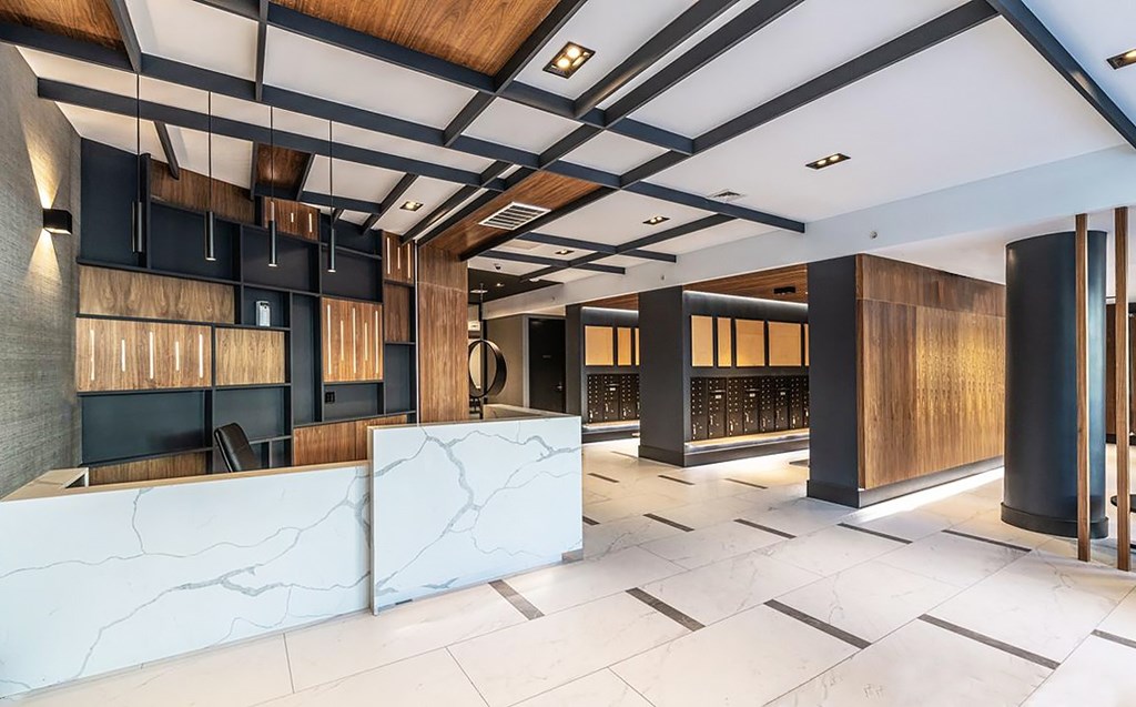 A modern office lobby with a white marble reception desk and wooden accents.
