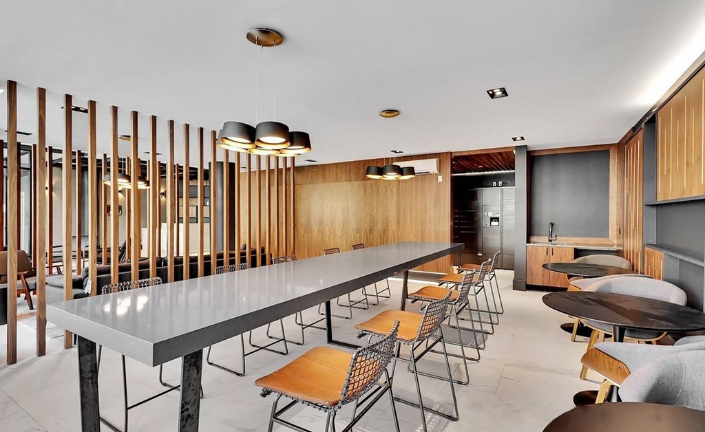 A long table with chairs is surrounded by wooden slats on the wall.
