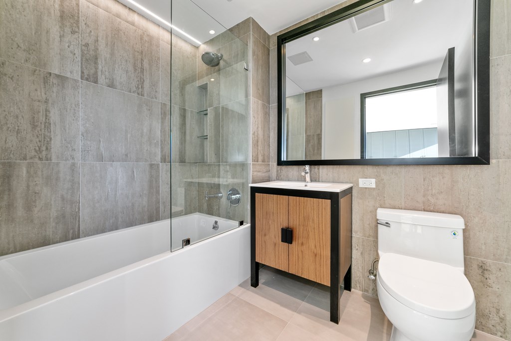 A modern bathroom with a wooden cabinet and a white toilet.