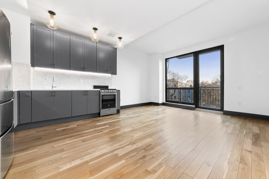 A kitchen with wooden floors and a large window.