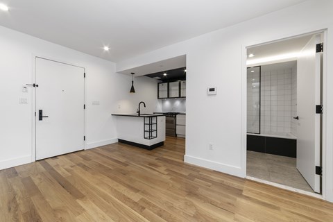 A kitchen with white walls and wooden floors.
