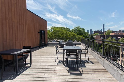 A wooden deck with a table and chairs overlooking a city skyline.