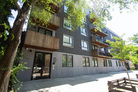 A modern building with balconies and a tree in front.