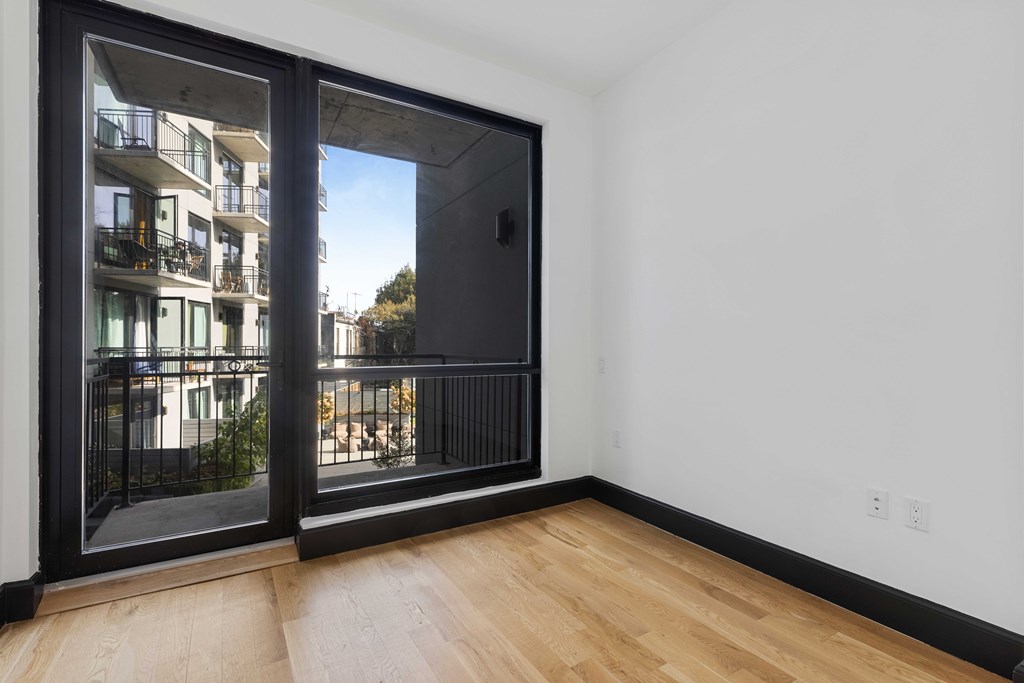 A room with a sliding glass door leading to a balcony with a railing.