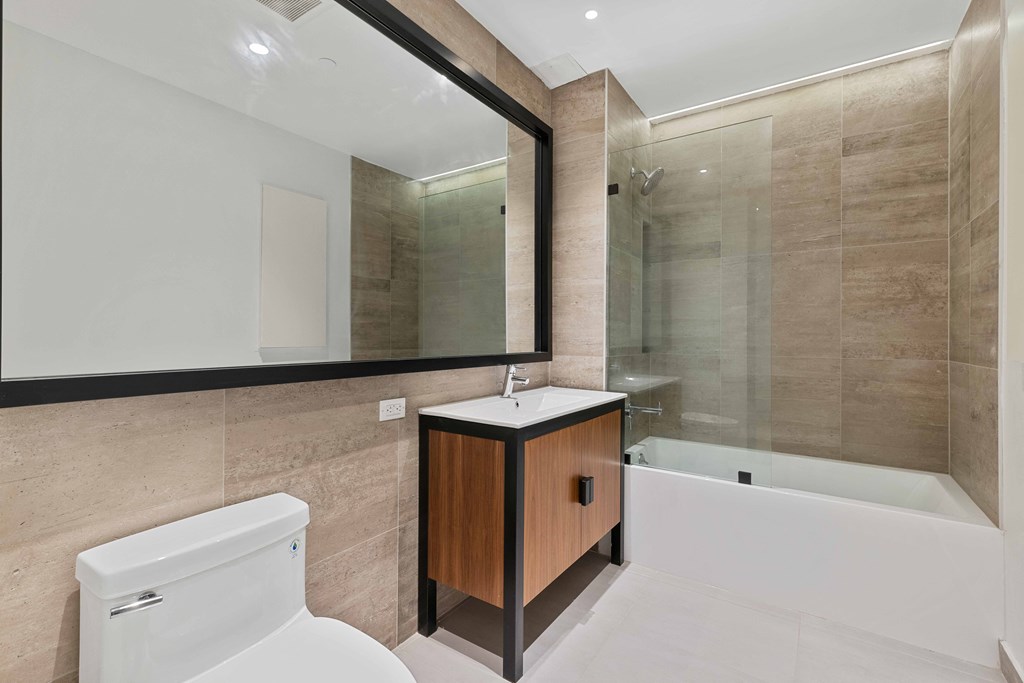 A modern bathroom with a white toilet and a wooden vanity.