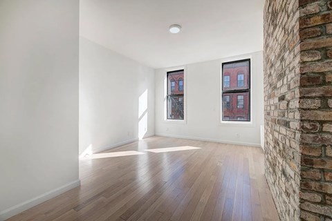 an empty living room with a brick wall and wood floors