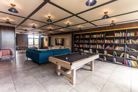 A room with a pool table and a bookshelf.
