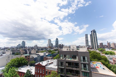 A cityscape with a mix of modern and older buildings under a partly cloudy sky.