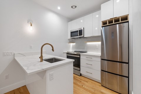 a white kitchen with stainless steel appliances and a white counter top