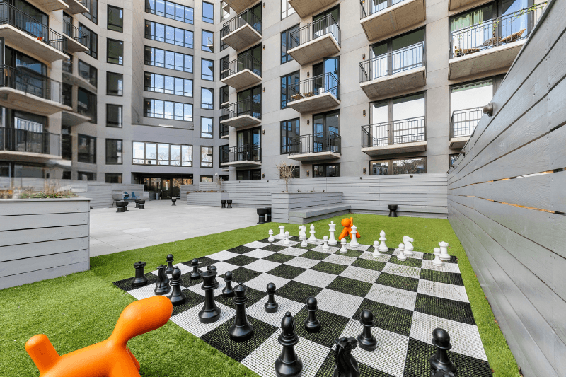 A giant chess board with pieces on a lawn in front of a building.