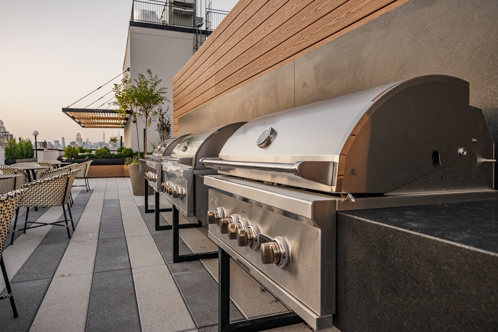 a barbecue grill on the patio of a restaurant with tables and chairs