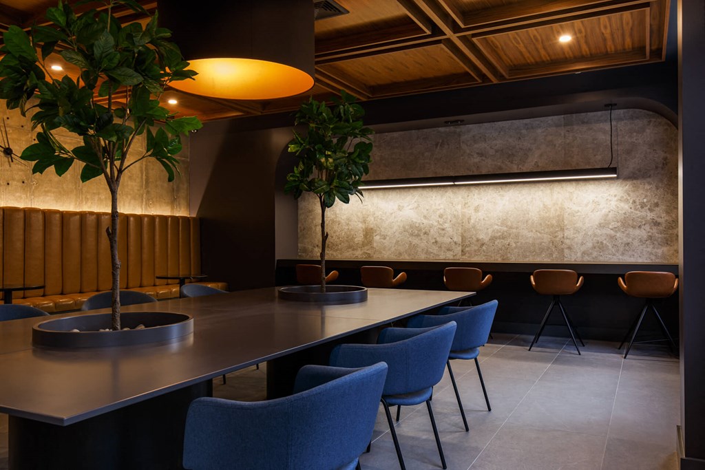 a long table with blue chairs and two trees in a lobby
