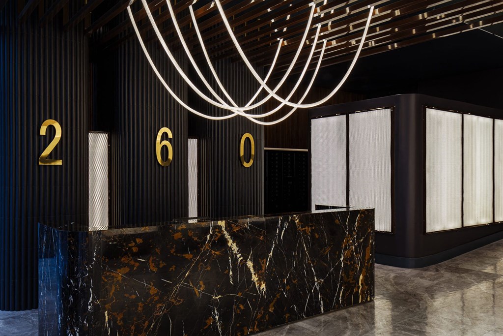a lobby with a black marble reception desk and a large light fixture