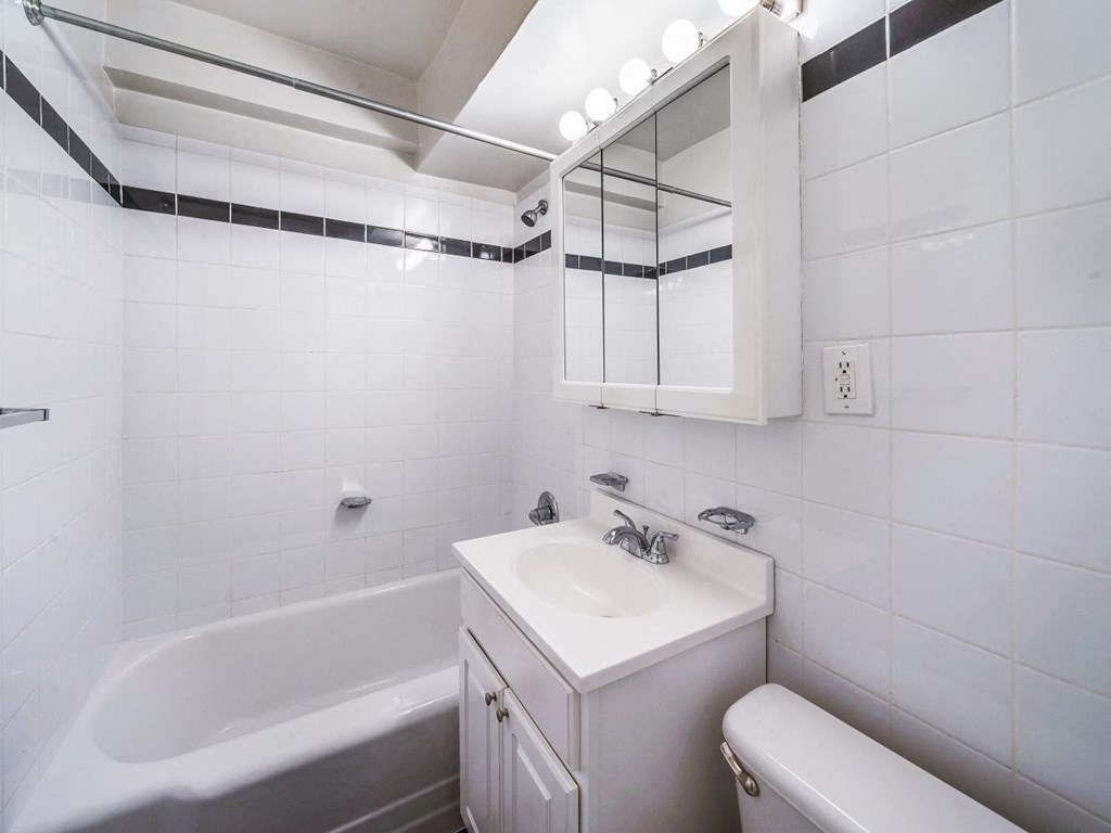 A white bathroom with a tub, sink, and toilet.