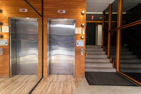 Two elevators are located in a wood and tile hallway.