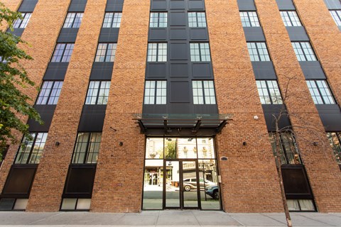 A tall brick building with a black awning and a glass doorway.