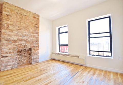 A room with a brick fireplace and wooden floors.