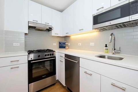 A modern kitchen with white cabinets and stainless steel appliances.