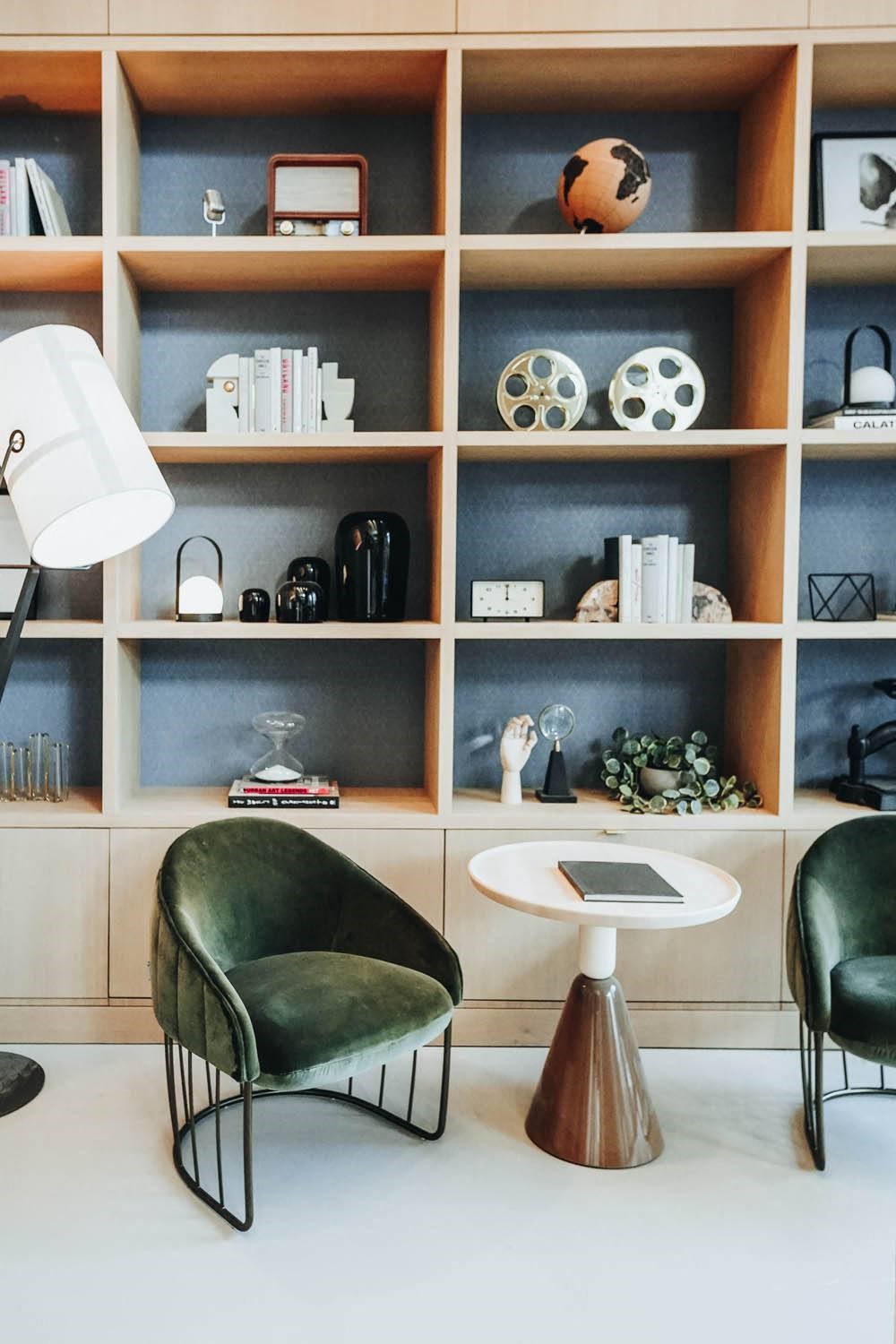 a living room with green chairs and a bookshelf at The Lively, Jersey City