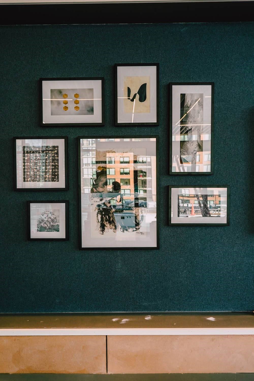 a row of pictures hanging on a wall with a green wall at The Lively, Jersey City, 07302