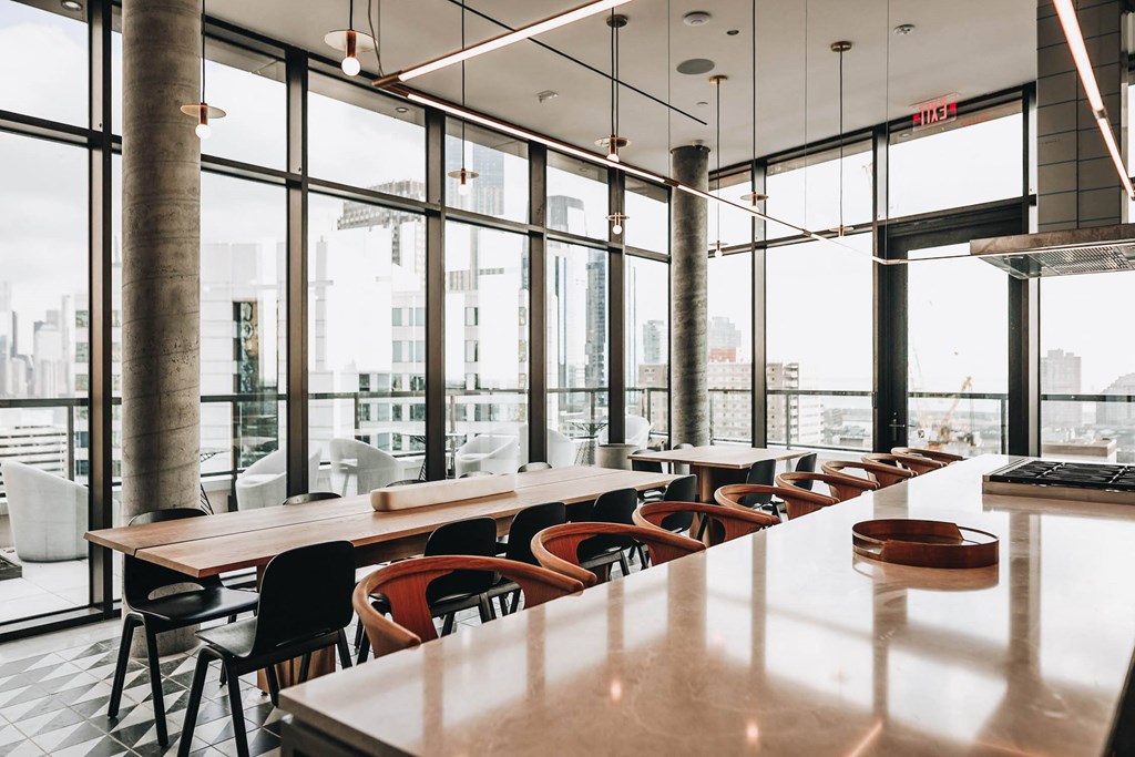 a long table and chairs in a restaurant with large windows at The Lively, Jersey City, NJ 07302