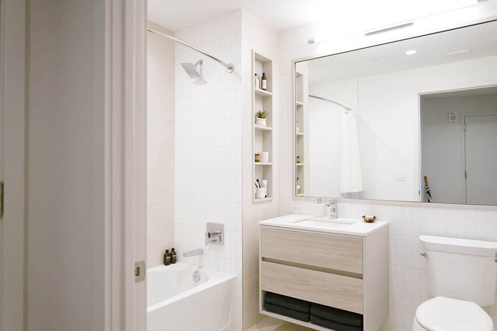 a white bathroom with a large mirror and a toilet and a sink at The Lively, Jersey City, 07302